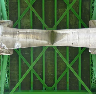 underside of a bridge with concrete supports and green rafters
