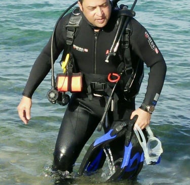 Captain Essam in a wetsuit is standing in the water