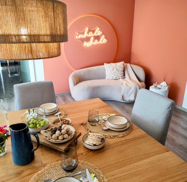 Ess-/Wohnzimmer in Retreathaus mit Couch im Hintergrund und Leckereien auf Esstisch im Vordergrund