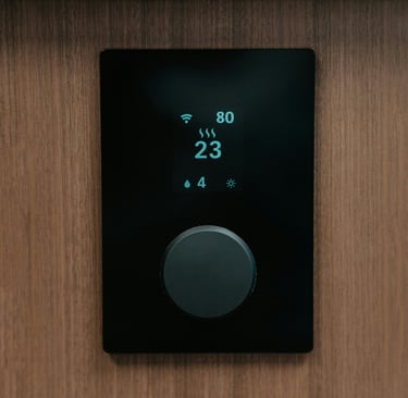 Smart digital thermostat with a black display and dial mounted on a wood wall for home climate control.