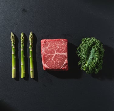 Raw wagyu beef steak with fresh green asparagus and kale on a dark stone background.