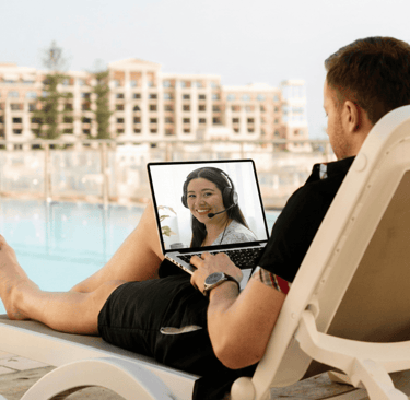 student in front of a pool resort in the backround while holding a computer with the face the tutor from Hola with Alo