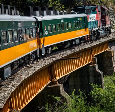 El tren El Chepe cruza un puente amarillo en la Barranca del Cobre, México, mostrando los vagones