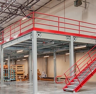 Industrial warehouse mezzanine floor with red safety handrails and steel staircase for storage.