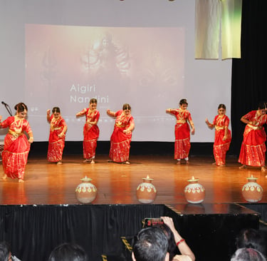 A vibrant group of young girls in traditional kathak attire performing a synchronized dance on stage