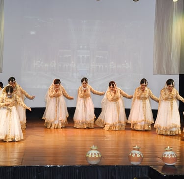A vibrant group of young girls in traditional kathak attire performing a synchronized dance on stage
