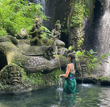 Woman bathing at a Bali waterfall. Highlights the spiritual travel a visa enables.