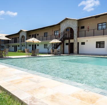 Luxury resort swimming pool with crystal clear water, patio umbrellas, and stone arch architecture.