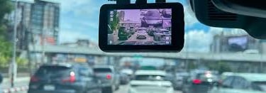 A car dash cam mounted on a windshield recording heavy city traffic for safety and evidence.