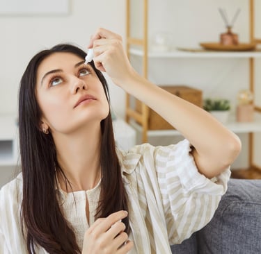 Woman putting eye drops in her eyes