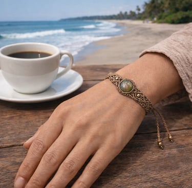 Pulsera artesanal de macramé con piedra natural sobre mesa de madera con café y playa de Campeche de fondo.