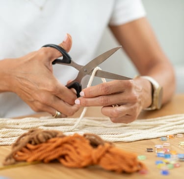 artesana cortando macramé con tijeras sobre una mesa