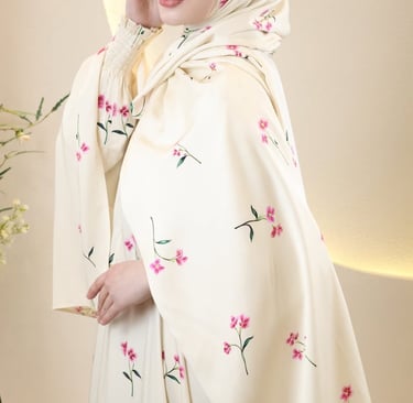 Elegant woman wearing a cream-colored floral hijab and matching abaya with pink flower prints.