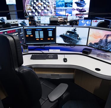 Security operations center workstation with multiple surveillance monitors and a large video wall.