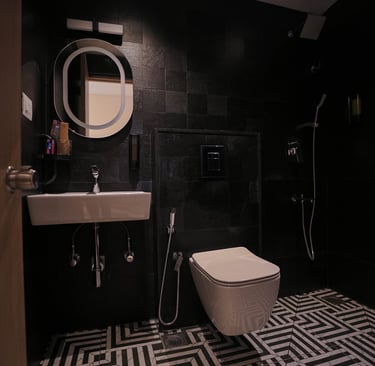 Modern luxury bathroom with black wall tiles, a white wall-hung toilet, and an illuminated mirror.