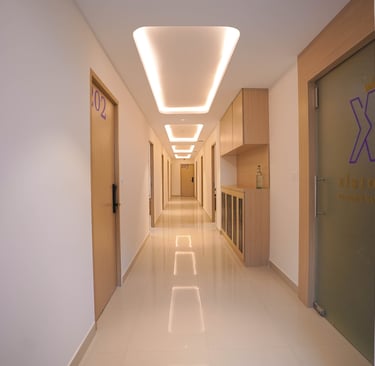 Modern hotel corridor featuring minimalist wood doors, bright white walls, and elegant recessed ceiling lighting.