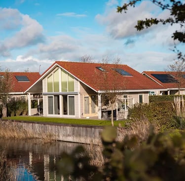  Luxuriöse Ferienhaus in einem Ferienpark direkt am Wasser mit Solaranlage und rotem Ziegeldach.