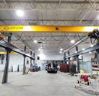 A large, bright yellow overhead bridge crane with SAFE LIFTING