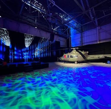 Military helicopter in a large hangar with dramatic blue and green event lighting and projection mapping.