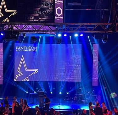 Pantheon de la Performance gala stage with blue spotlighting, corporate sponsor logos, and event signage.