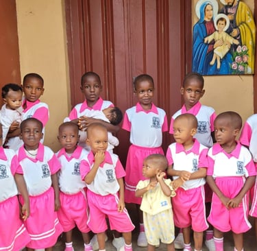 Group of African schoolchildren in pink uniforms posing together outside near a religious painting.