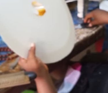 Close-up of a person holding a white circular craft template in a workshop setting.