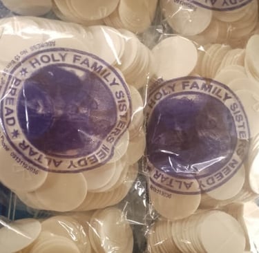 Stacks of white altar bread communion wafers in plastic bags from Holy Family Sisters.