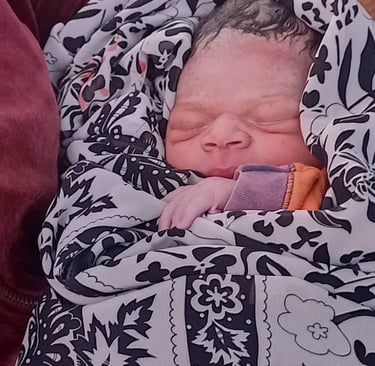 A sleeping newborn baby wrapped in a black and white patterned floral swaddle blanket.