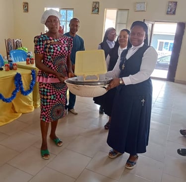 Catholic nuns presenting a donation basin to a woman in a colorful dress during a community outreach event.