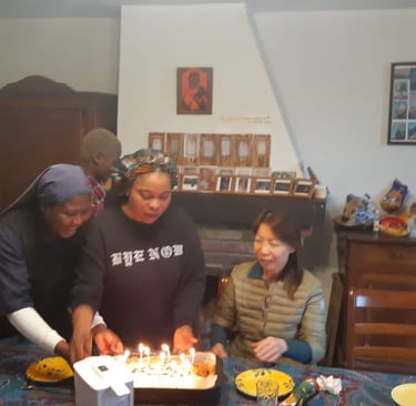 Friends celebrate a birthday together with a glowing candle-lit cake at a dinner party.