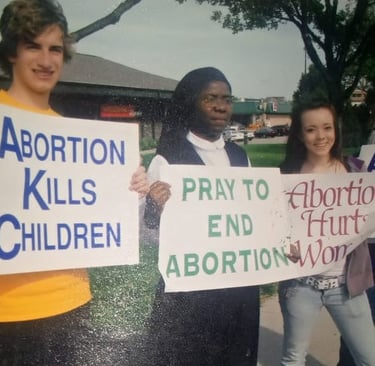 A group of pro-life protesters including a nun holding anti-abortion signs at a public demonstration.