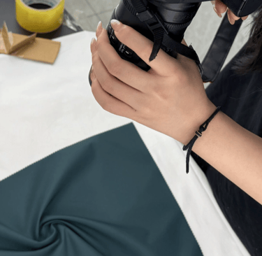 Photographer shooting YL fabric in deep blue velvet on a white table with a DSLR camera.