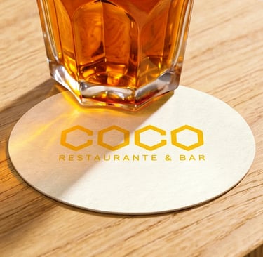 Posavasos con la marca sobre mesa de madera junto a un cóctel