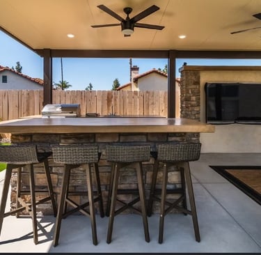 a patio with a bar stool and a ceiling fan