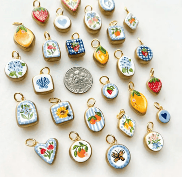 Charms personalizados de diferentes formas y colores sobre un fondo beige