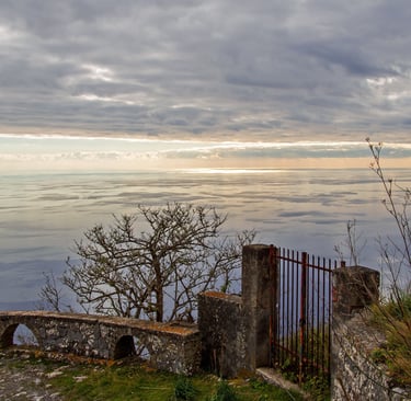 Vista panoramica di Maratea da un balcone in pietra con un cancello sotto un cielo nuvoloso