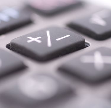 Extreme close-up of a digital calculator keypad focusing on the plus and minus arithmetic symbol keys.