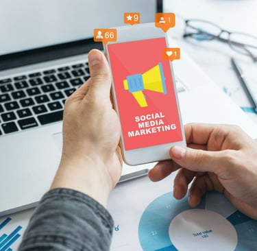 A person holding a smartphone displaying a social media marketing graphic next to a laptop and data charts.