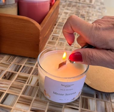 Pessoa acendendo uma vela de massagem artesanal da Raiz & Encanto com pavio de madeira.