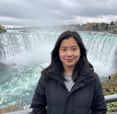 Close-up of one woman laughing with mist from Niagara Falls softly blurring the background.