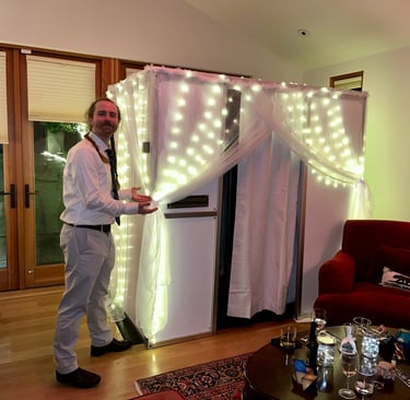 Mace from Bhoto Booth standing next to enclosed photo booth with fairy light draping at a Bay Area w