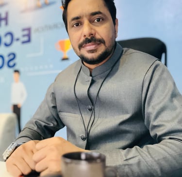 Professional male entrepreneur in a gray waistcoat sitting at an office desk with a coffee mug.