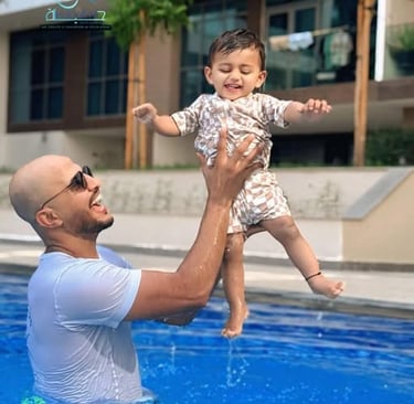 Smiling coach holding up his student during a fun swimming lesson in an outdoor pool.