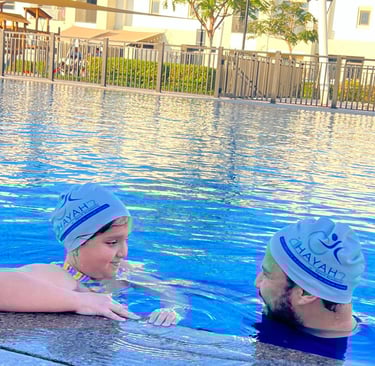 A young girl receives a private swimming lesson from an instructor in an outdoor pool.
