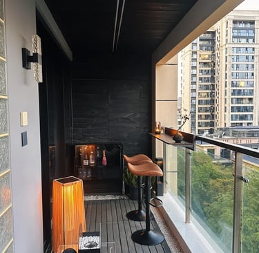 Cozy small balcony with space-saving furniture, soft cushions, potted plants, and warm evening light