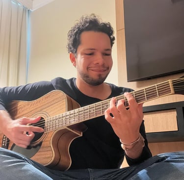Músico e palestrante autista Lucas Sampaio, com violão marrom em quarto de hotel.