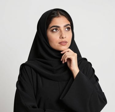 Thoughtful young Arab woman wearing a modest black hijab and modest abaya looking upwards.