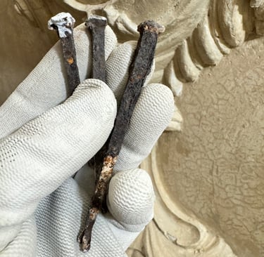 Roestige gesmede spijkers in het stucwerk.