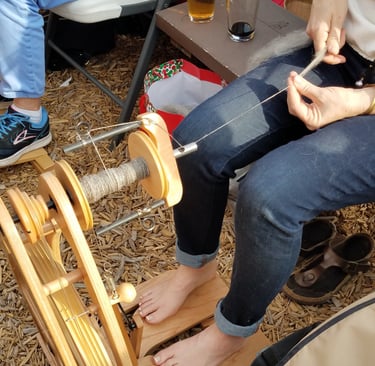 A close-up of someone spinning thread on a spinning wheel while attending First Magnitude Brewery.