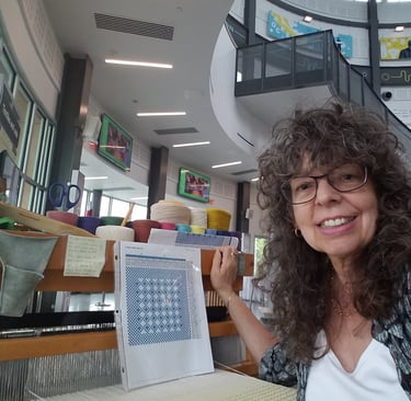 Linda at the Cade Museum showing her loom and a weaving pattern.